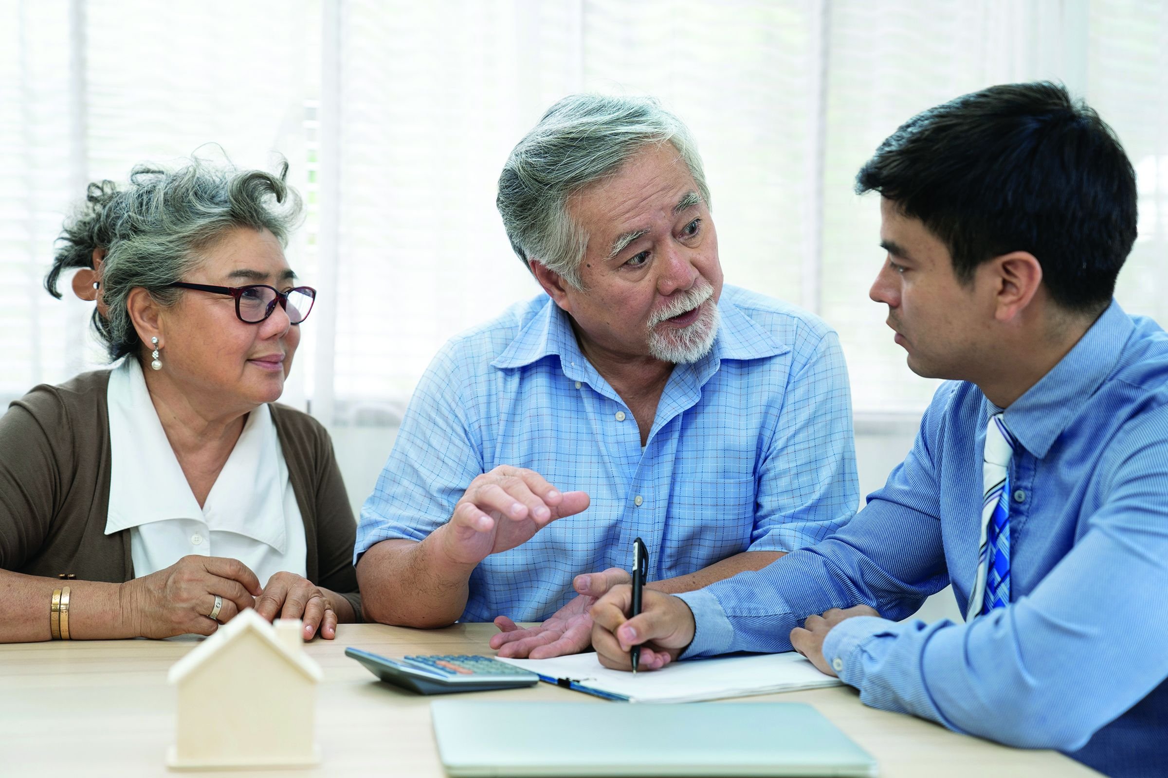 An insurance agent offers health insurance for Asian elderly couples, Finance staff present and close real estate sales.
